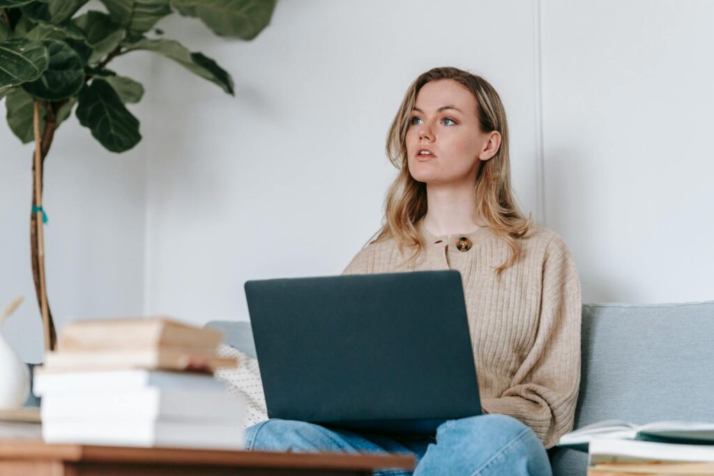 Thoughtful woman with laptop working at table with books