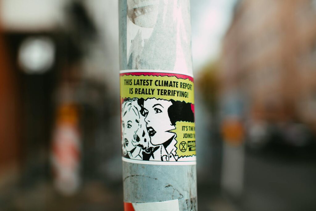 Sticker on pole with comic-style graphics raising awareness about climate change.