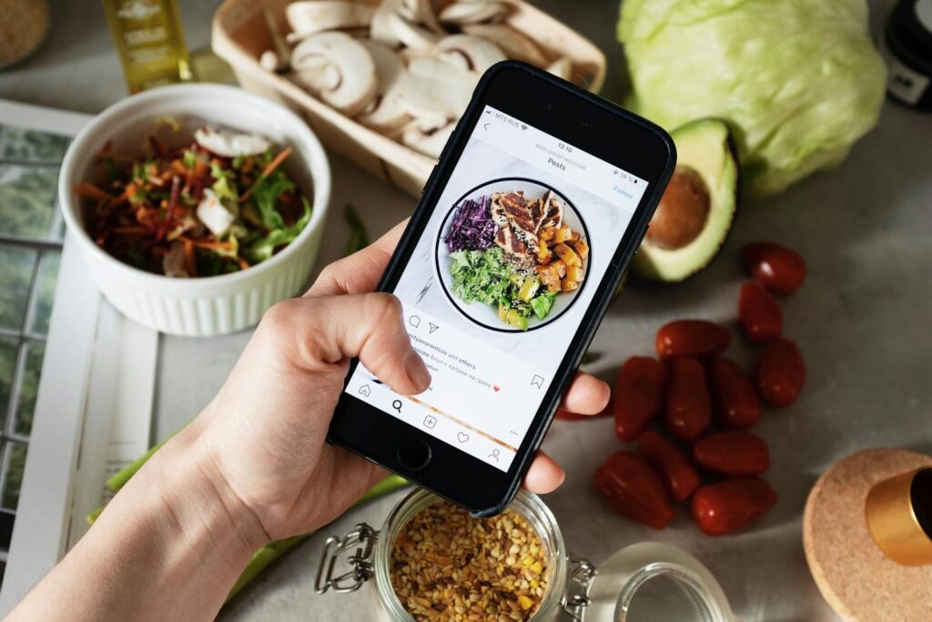 Person takes photo of healthy salad ingredients for social media in kitchen.