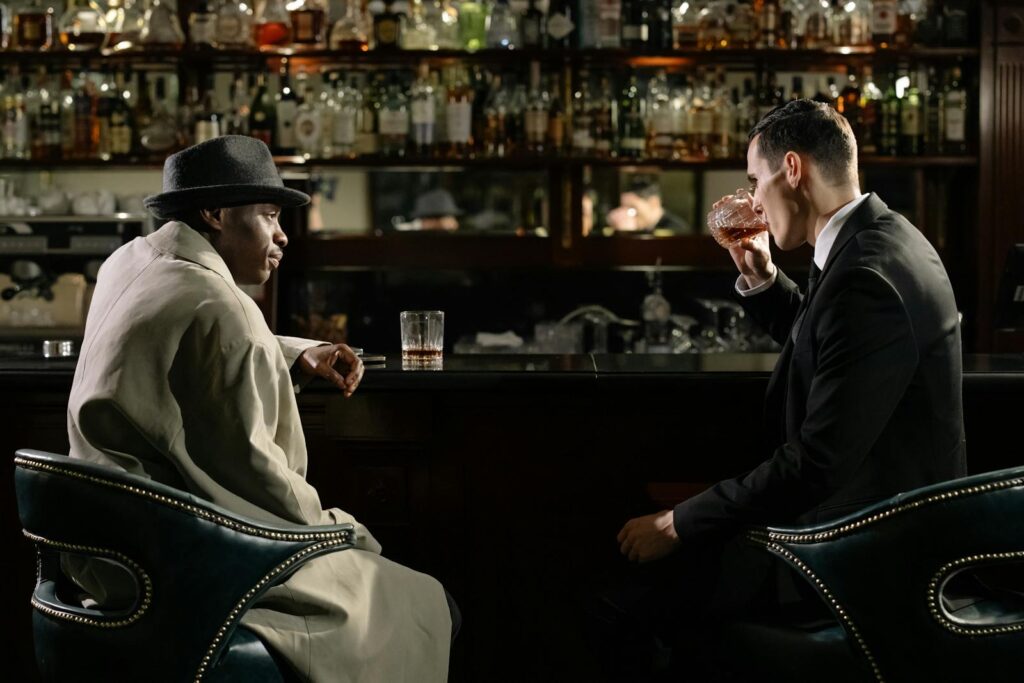 Men in a dimly lit bar engage in serious discussion over drinks.